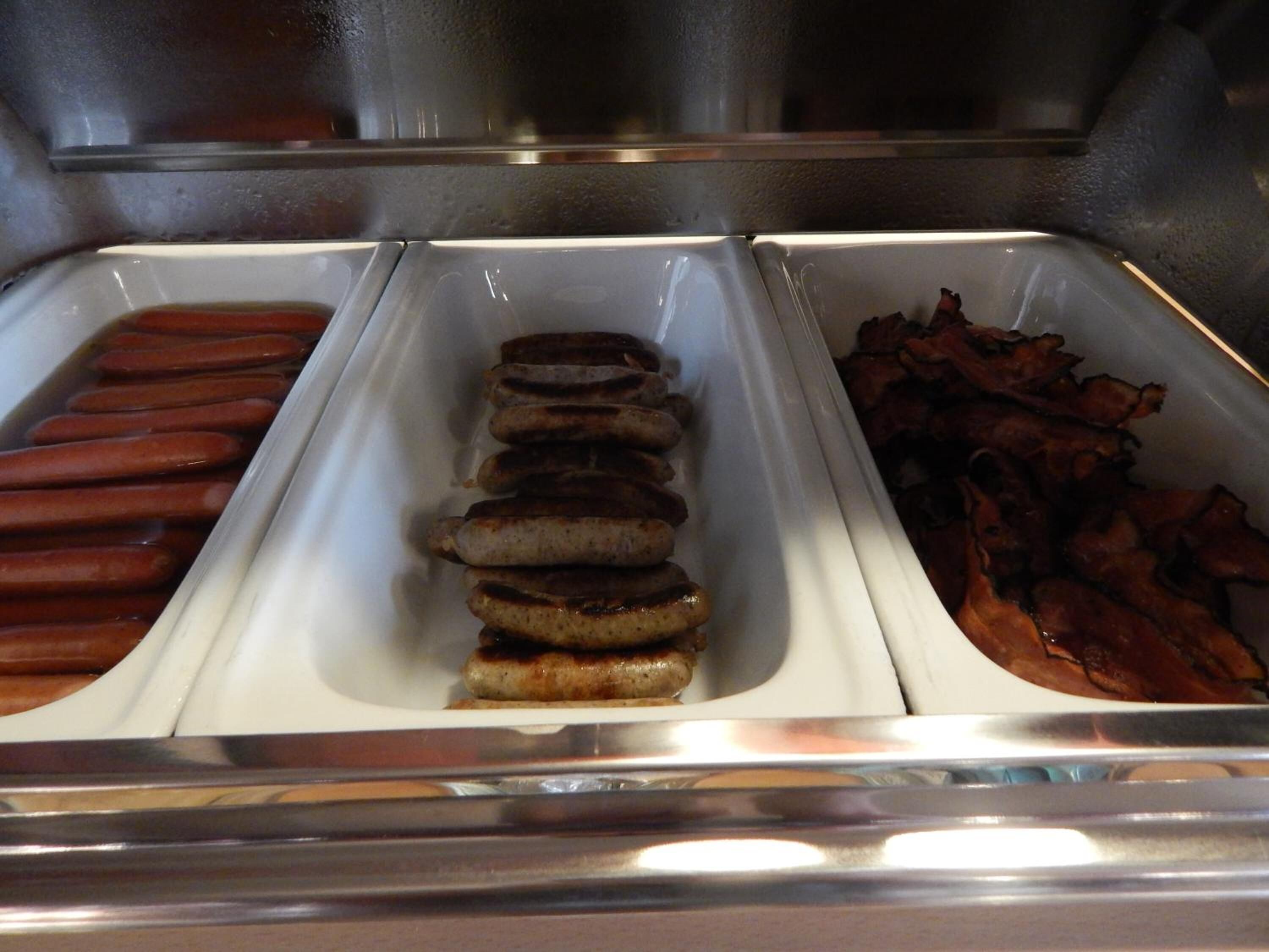 A buffet with hot dogs and bacon.