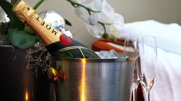 A bottle of Moët champagne in a metallic bucket with a glass beside it, set against a backdrop of white flowers and a candle.