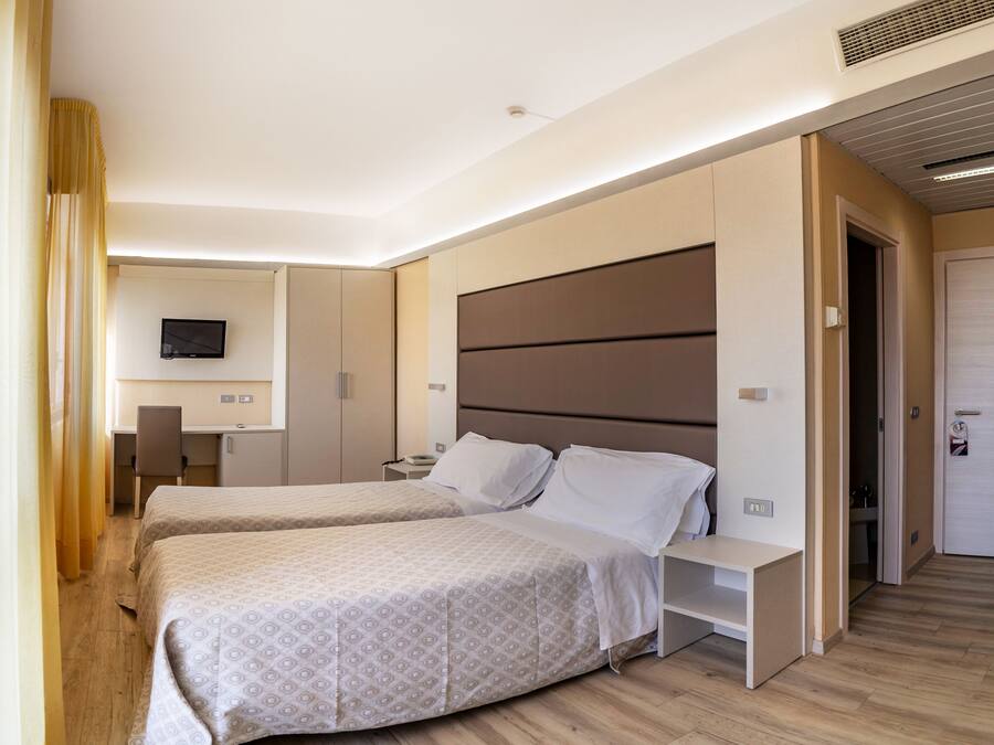 A hotel room with two beds, a desk, and a TV.