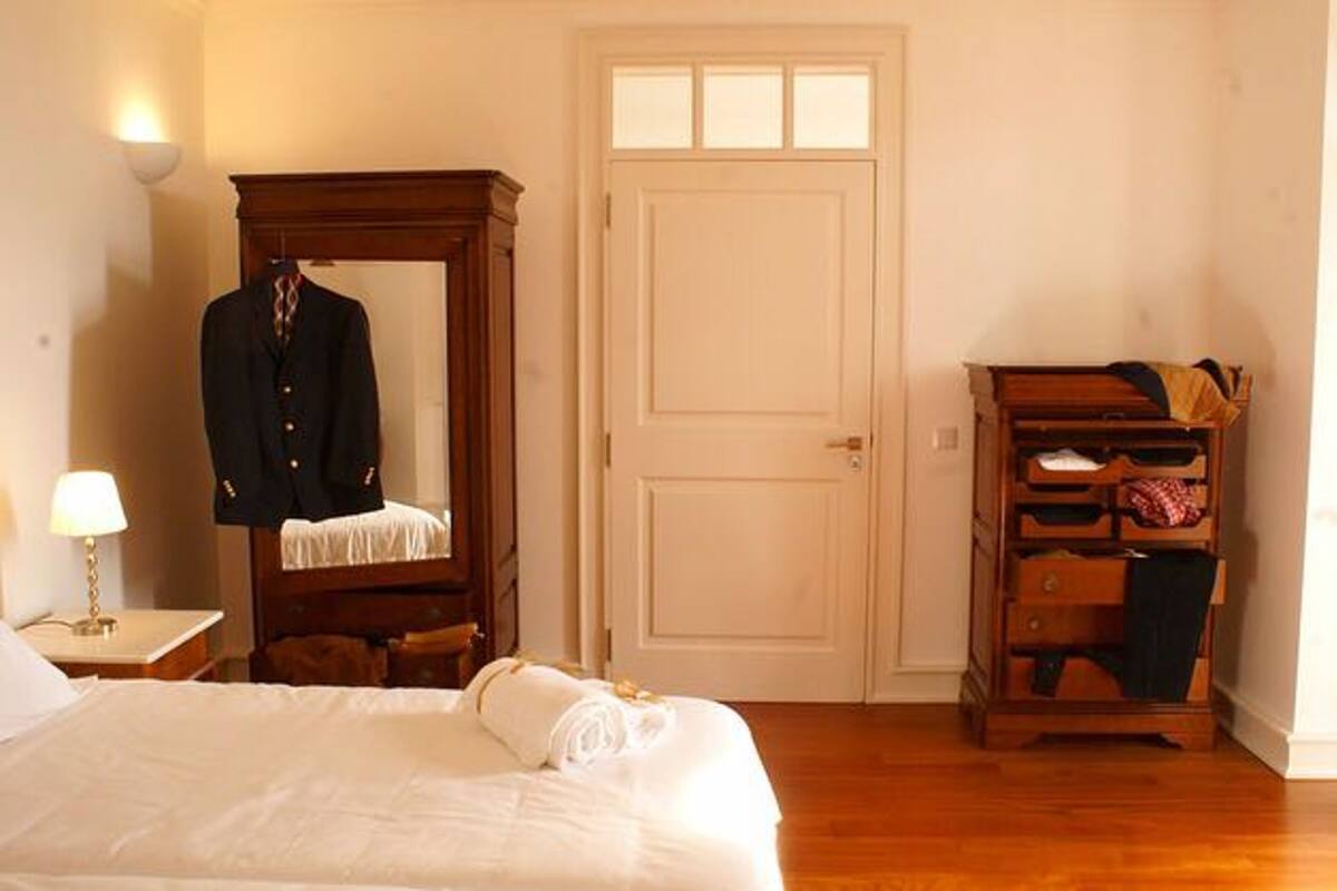 A hotel room with a bed, a wardrobe, a mirror, and a door.