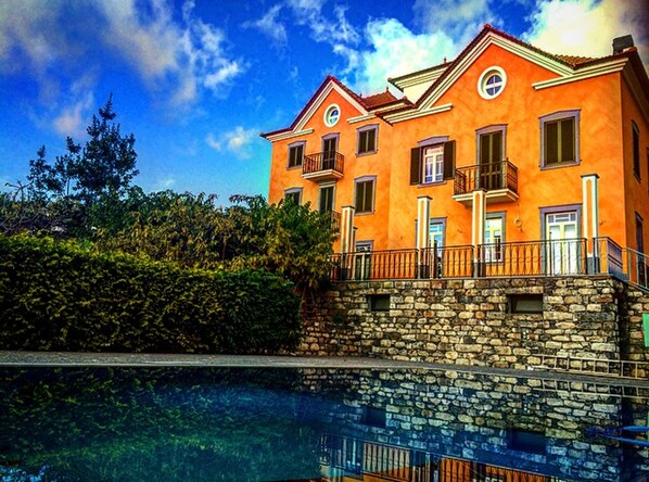 A two-story building with a stone base and a bright orange facade, featuring balconies and windows.