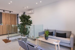 Una sala de estar moderna con un sofá gris, una mesa de centro de madera y una planta en maceta.