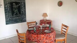 Un coin repas avec une table dressée pour quatre personnes, une lampe et un mur orné d’un tableau encadré.