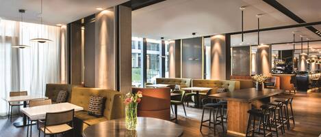 A modern interior with a bar area, seating, and a round table with a vase of flowers.