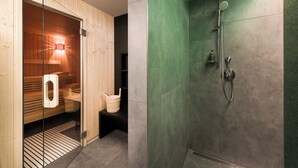 A modern bathroom with a sauna, a glass-enclosed shower area, and a wooden bench. - Adina Apartment Hotel Hamburg Speicherstadt (Hamburg)