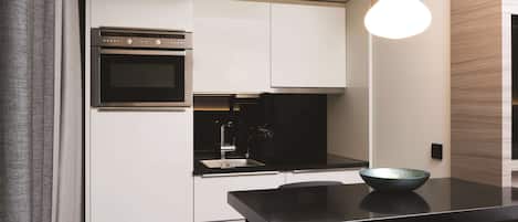 A modern kitchen with white cabinets, a black countertop, and a hanging light fixture.