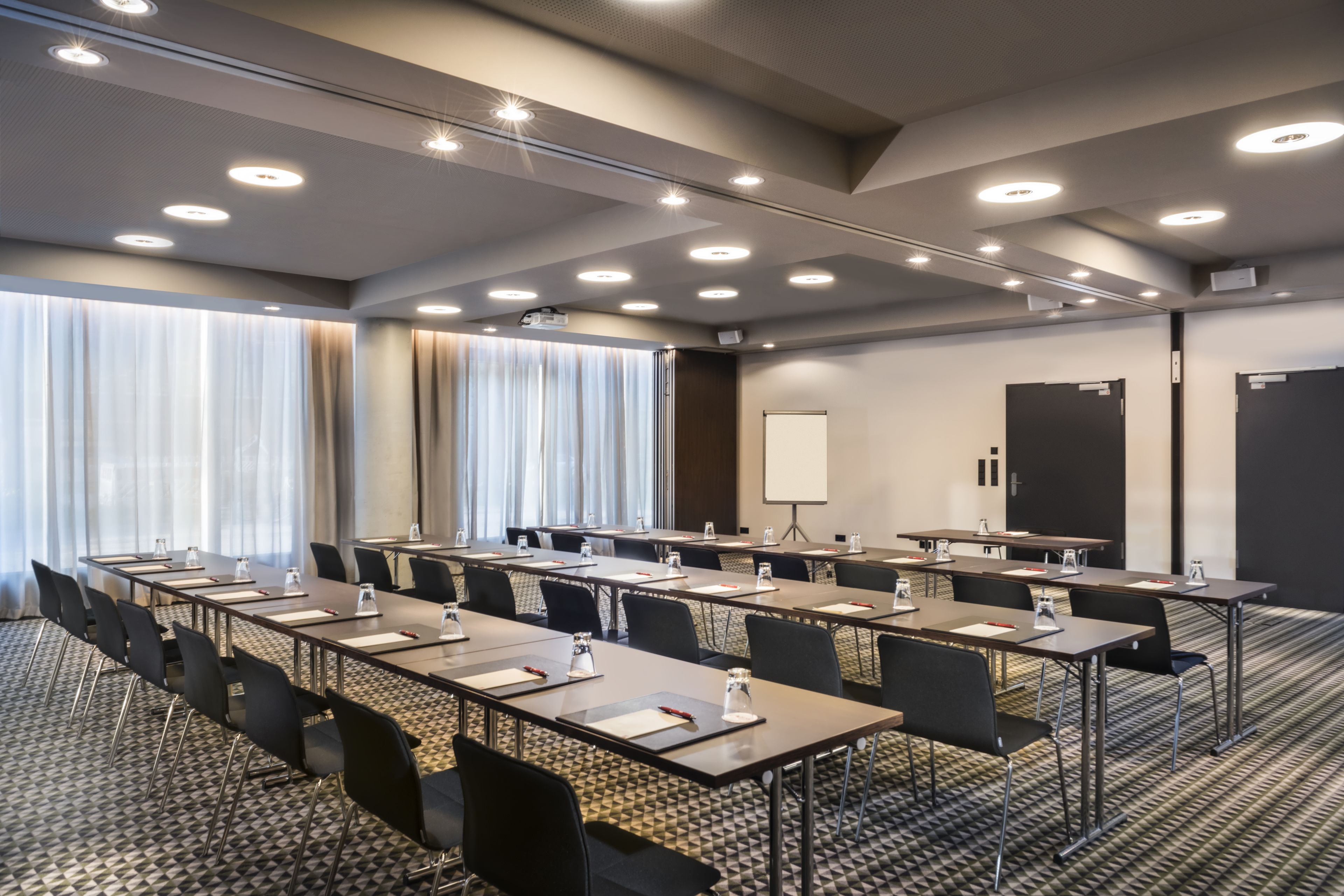 A conference room with multiple tables and chairs, a whiteboard, and a projector screen.