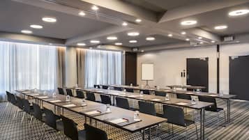 A conference room with multiple tables and chairs, a whiteboard, and a projector screen.