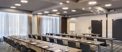 A conference room with multiple tables and chairs, a whiteboard, and a projector screen.