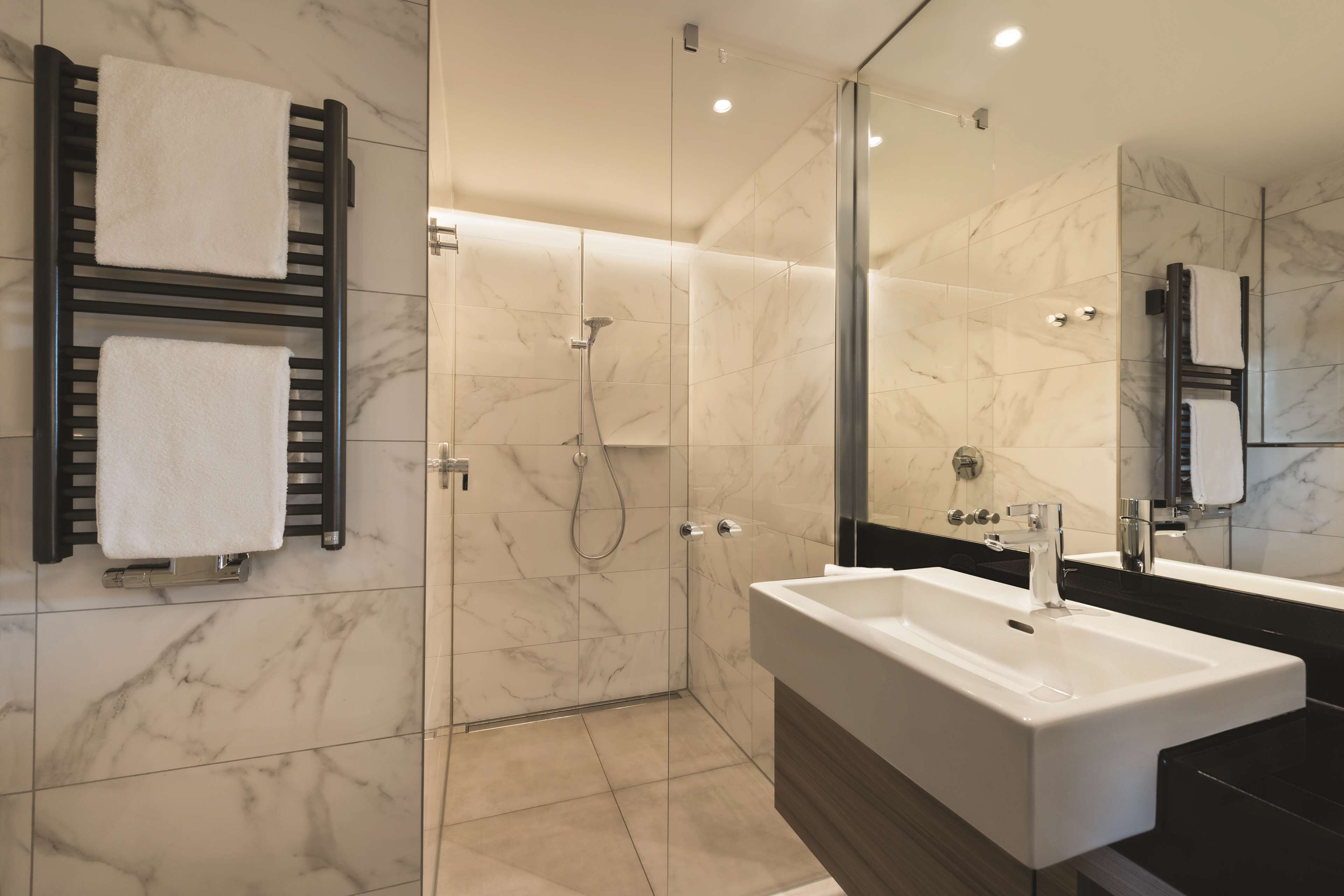 A modern bathroom with a glass-enclosed shower, a large sink, and a mirror.