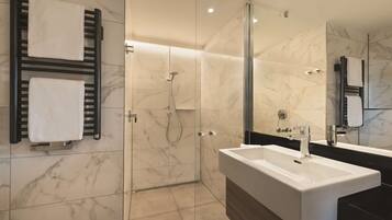 A modern bathroom with a glass-enclosed shower, a large sink, and a mirror.