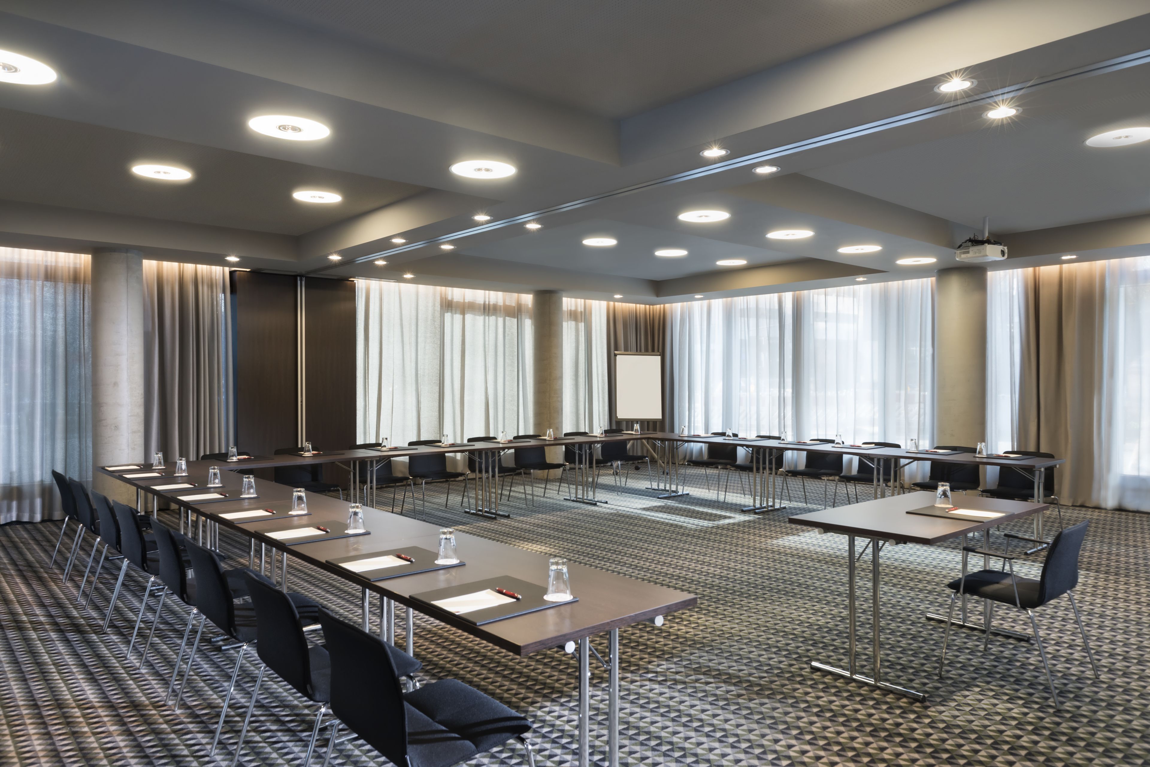 Une salle de conférence équipée d’une longue table, de chaises et d’un écran de projection.