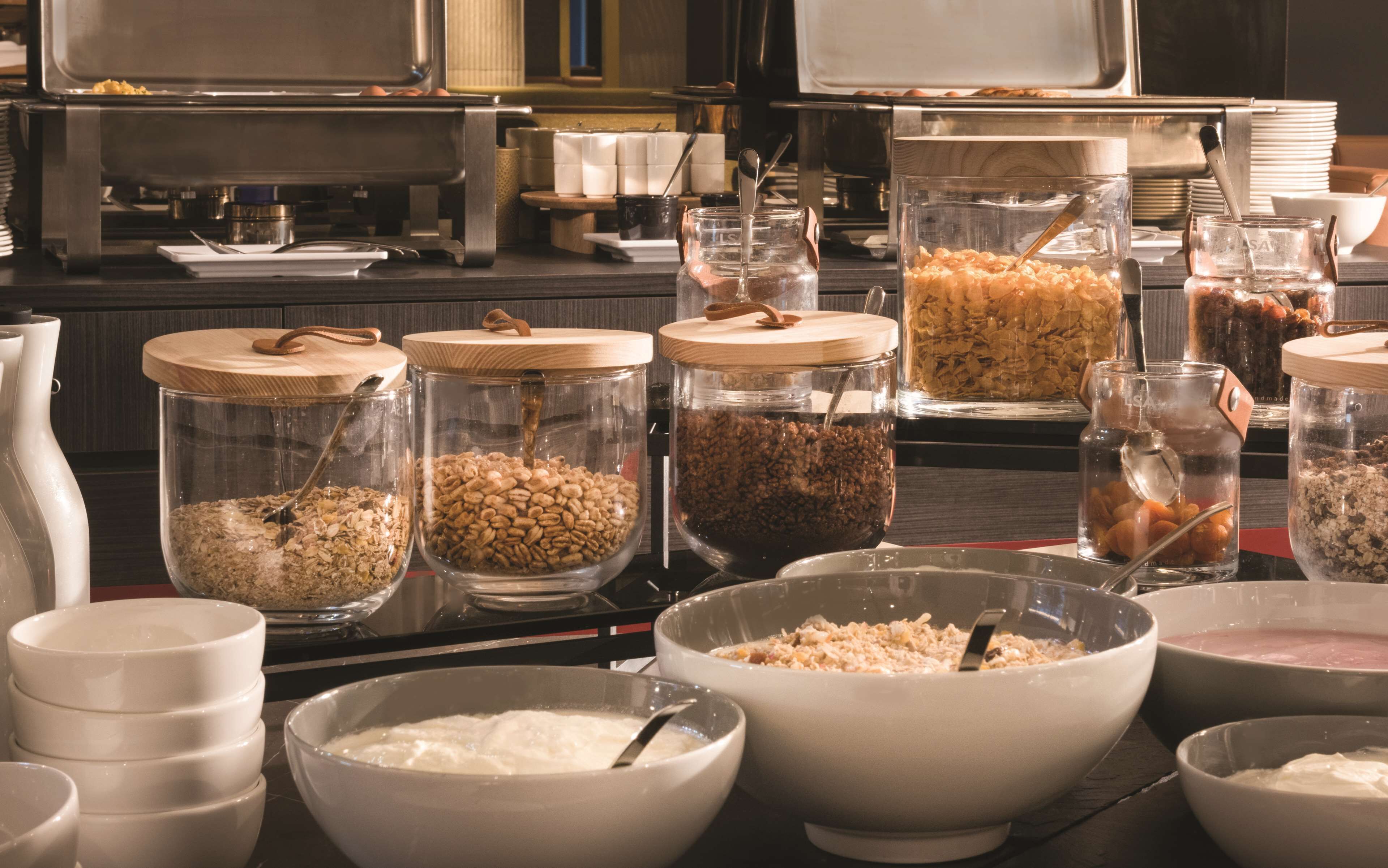 Una disposición de bufé con diferentes alimentos en recipientes y cuencos de vidrio.