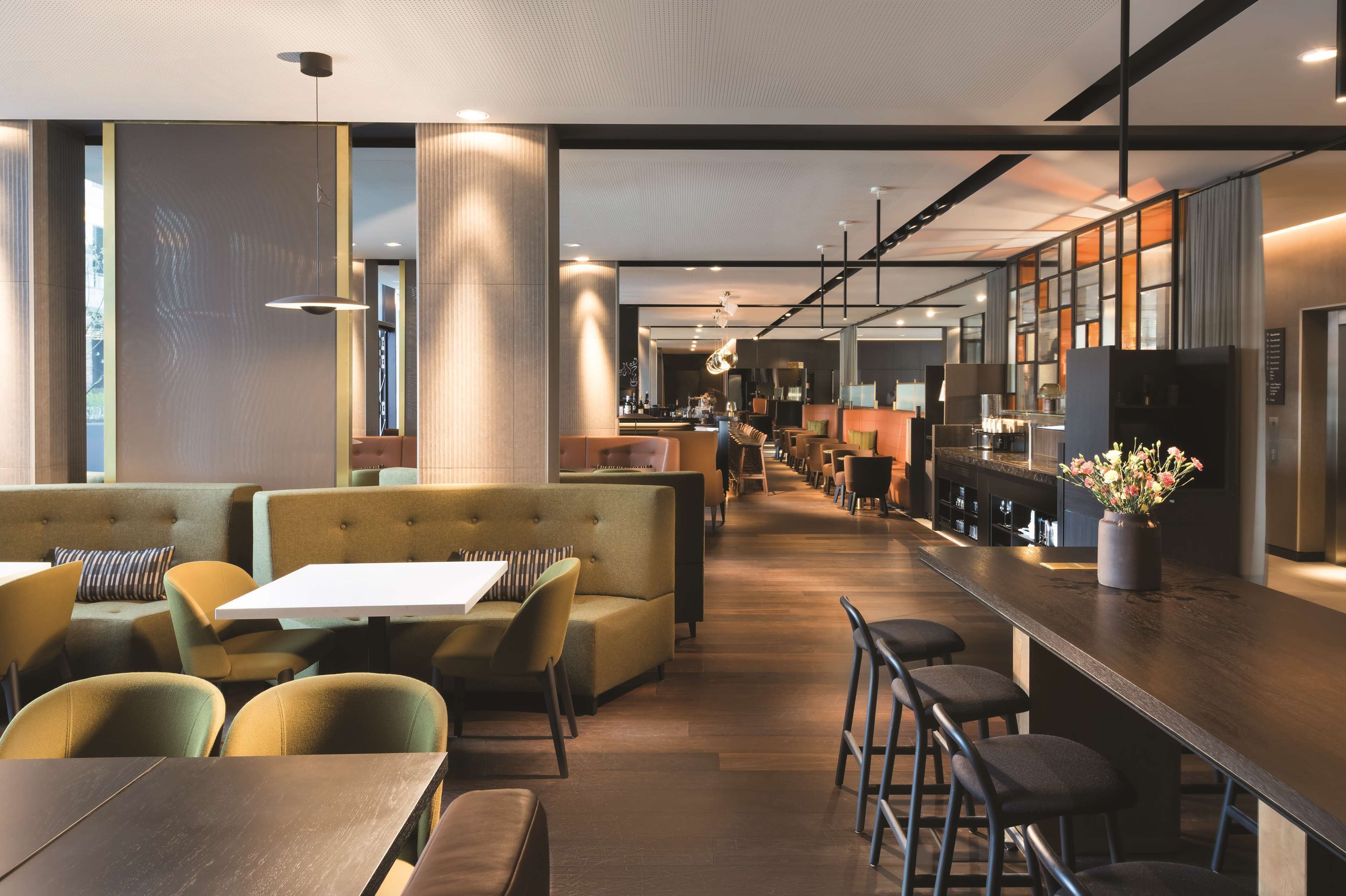 Un restaurant moderne avec des tables hautes, des banquettes et un long comptoir.