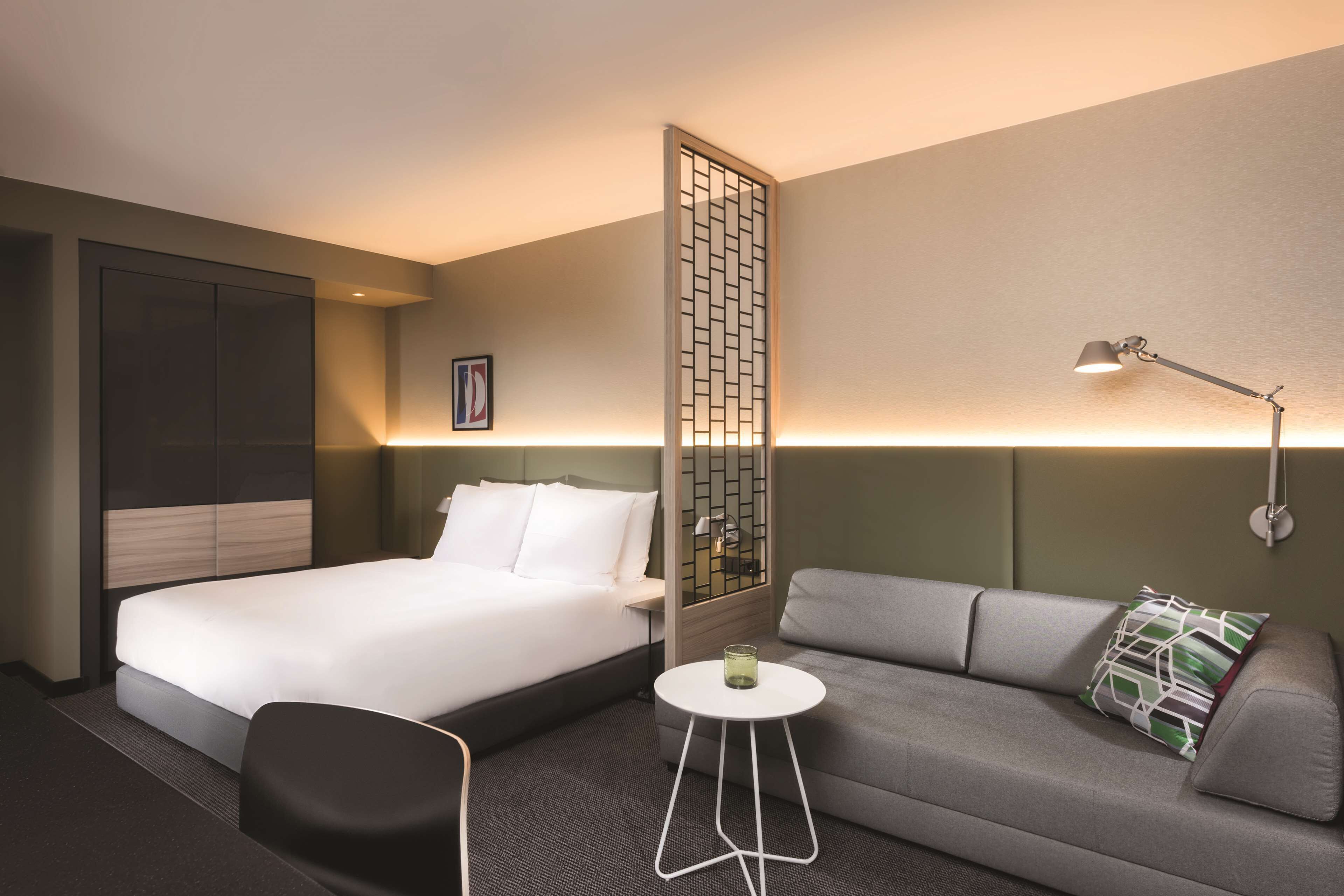 Ein Hotelzimmer mit Bett, einer Couch, einem kleinen Tisch und einer Wandlampe.