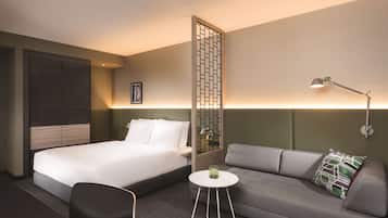 Ein Hotelzimmer mit Bett, einer Couch, einem kleinen Tisch und einer Wandlampe.