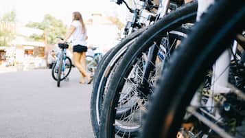 Bicicletas estacionadas en fila, una persona caminando al fondo y un edificio con un letrero.