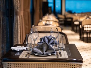A dining table set with wine glasses, a folded napkin, and cutlery. - Era Cruise Halong Bay by Venus Group (Ha Long)