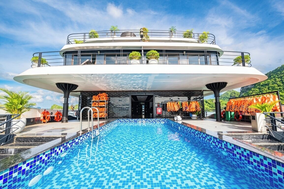 A modern hotel with a rooftop pool, a second floor balcony with plants, and a view of the surrounding landscape.