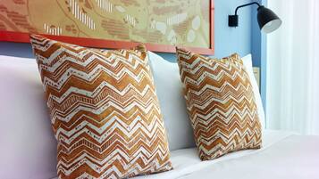 Two pillows with a zigzag pattern on a white sofa against a blue wall with a patterned artwork above.