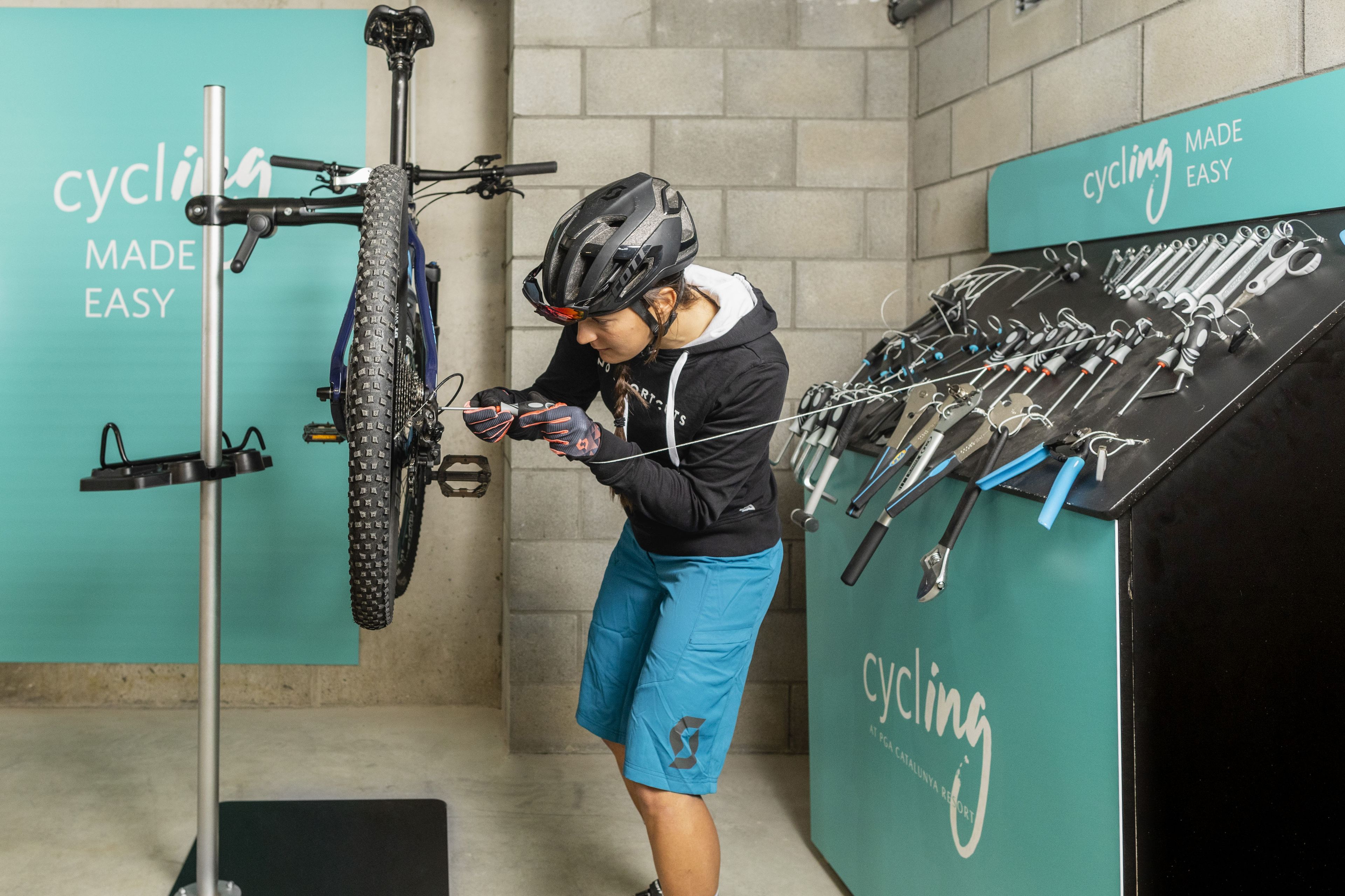 Een fietser in een kamer met een fietsenrek aan de muur en een gereedschapskist voor fietsen.