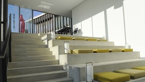 A staircase with concrete steps and yellow cushions, leading to a balcony with a railing and a view of a building.