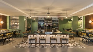 A modern bar with a central bar counter, multiple seating areas, and a ceiling fan.
