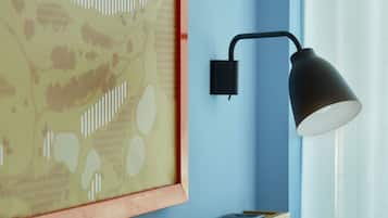 Una lámpara de pared, una obra de arte enmarcada y una estantería con libros.