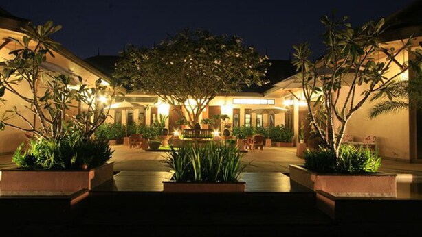A well-lit courtyard with a central seating area, surrounded by potted plants and a building with a warm glow. - Calvary Home (Mae Rim)