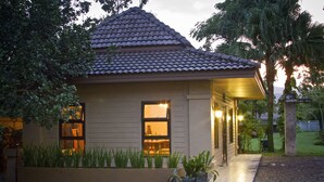 A house with a tiled roof, a covered porch, and a well-maintained garden. - Calvary Home (Mae Rim)