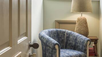 A room with a wooden door labeled "Alnourth," a patterned armchair, a lamp, and a view through a window.