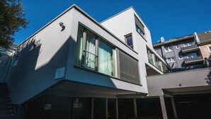 A modern building with a sloped roof, large windows, and a garage area. - Car by Side (Heidelberg)