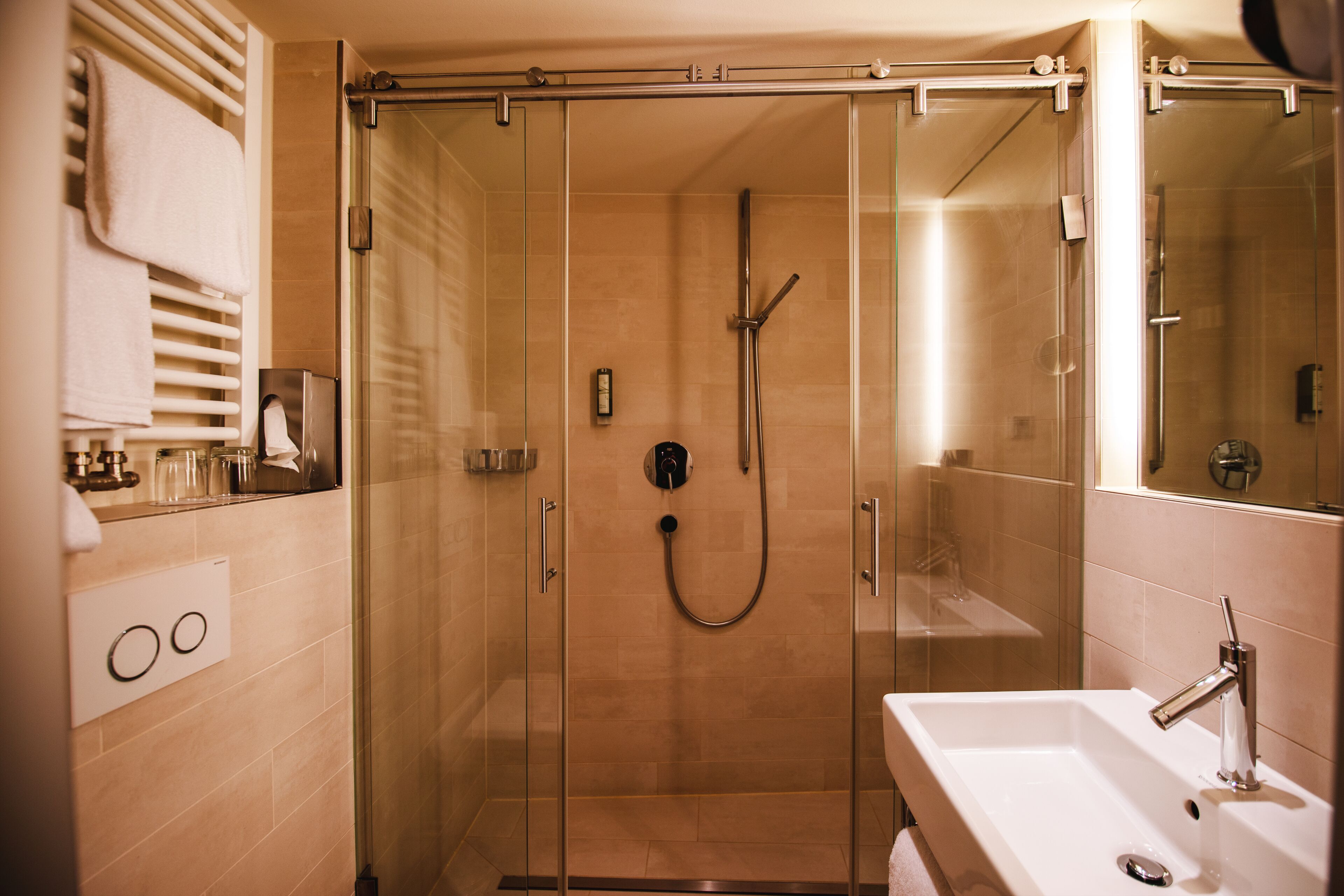 A modern bathroom with a glass-enclosed shower, a white sink, and a mirror.