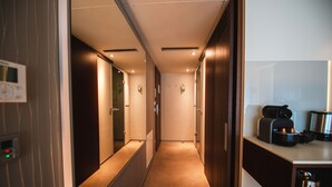 A hotel corridor with a coffee machine and a kettle on a counter, a thermostat on the wall, and a mirror reflecting the corridor. - Car by Side (Heidelberg)