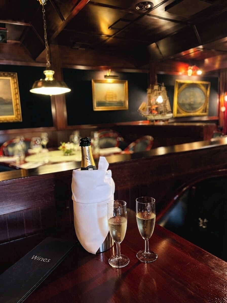 Zona de bar con una botella de champán, dos copas y un menú que dice 'Vinos'.