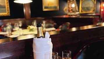 Zona de bar con una botella de champán, dos copas y un menú que dice 'Vinos'.