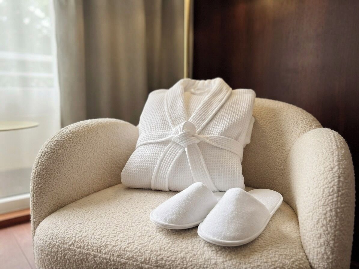 A plush armchair with a white bathrobe and slippers placed on it.