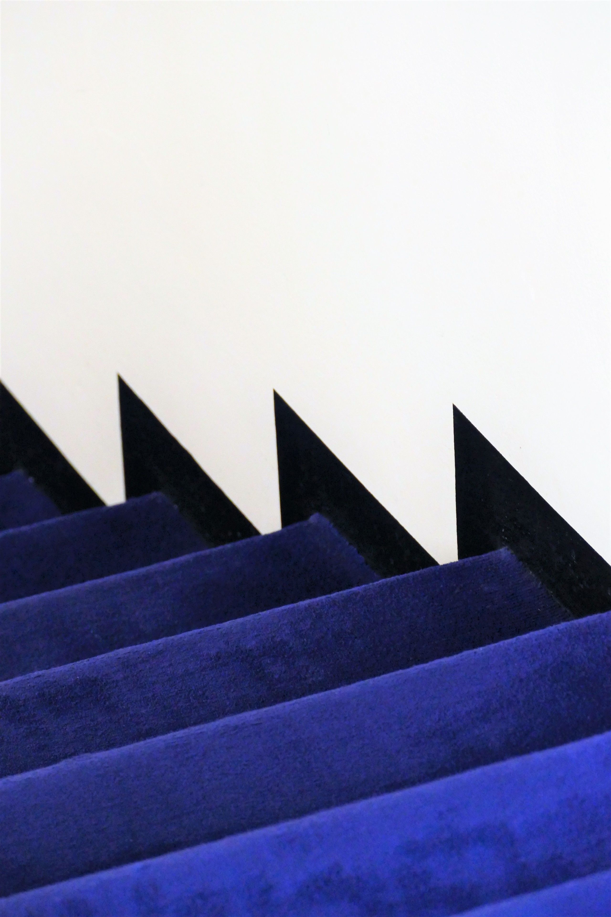 Escadas com carpete azul e corrimãos pretos.