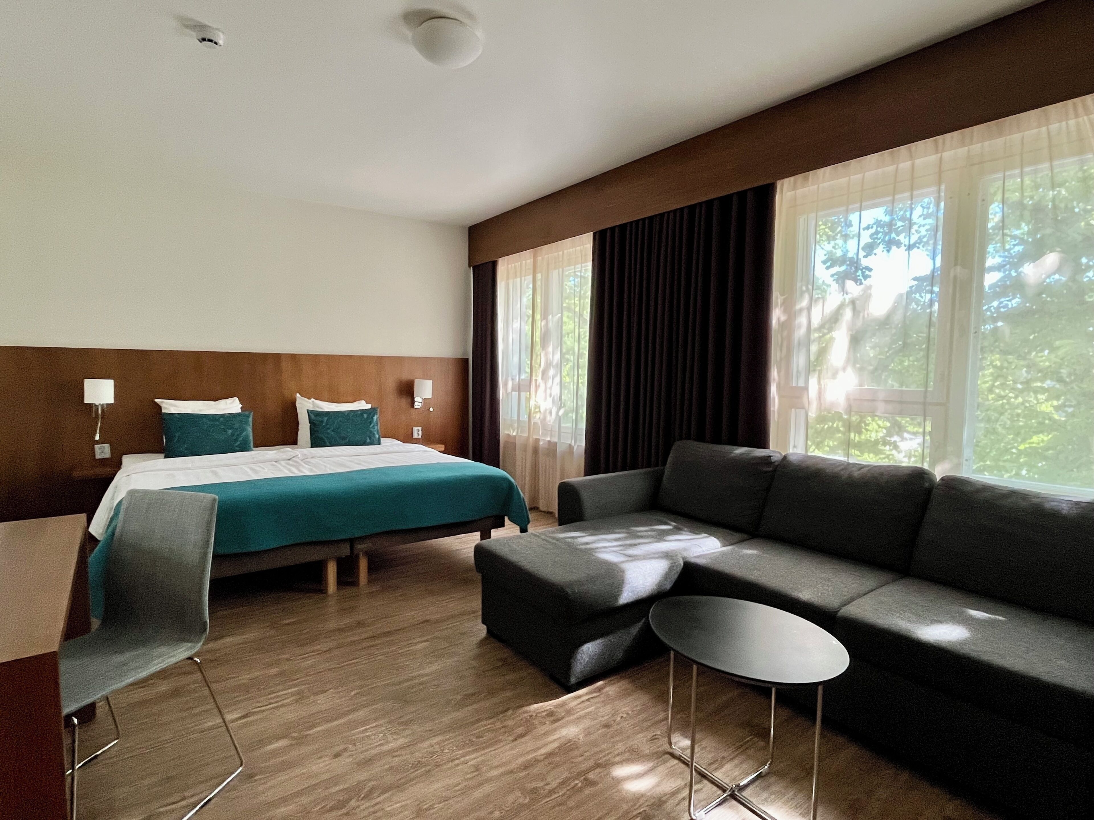 Une chambre d’hôtel avec un lit, un canapé, une petite table et une chaise.