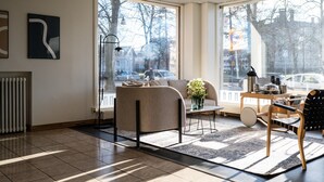 A modern living room with a large window, a radiator, a sofa, a coffee table, and a chair. - Hotel Raumanlinna (Rauma)