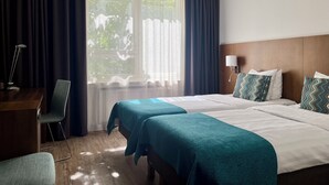 A hotel room with two beds, a desk, a chair, a lamp, and a window with curtains. - Hotel Raumanlinna (Rauma)