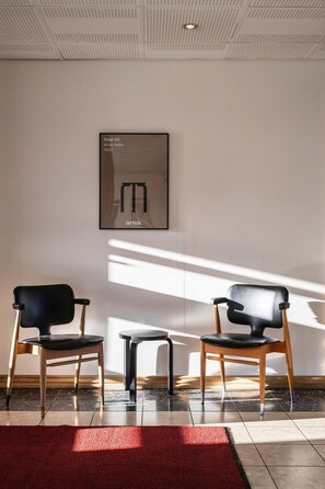 A waiting area with two black chairs, a small table, and a framed artwork on the wall. - Hotel Raumanlinna (Rauma)