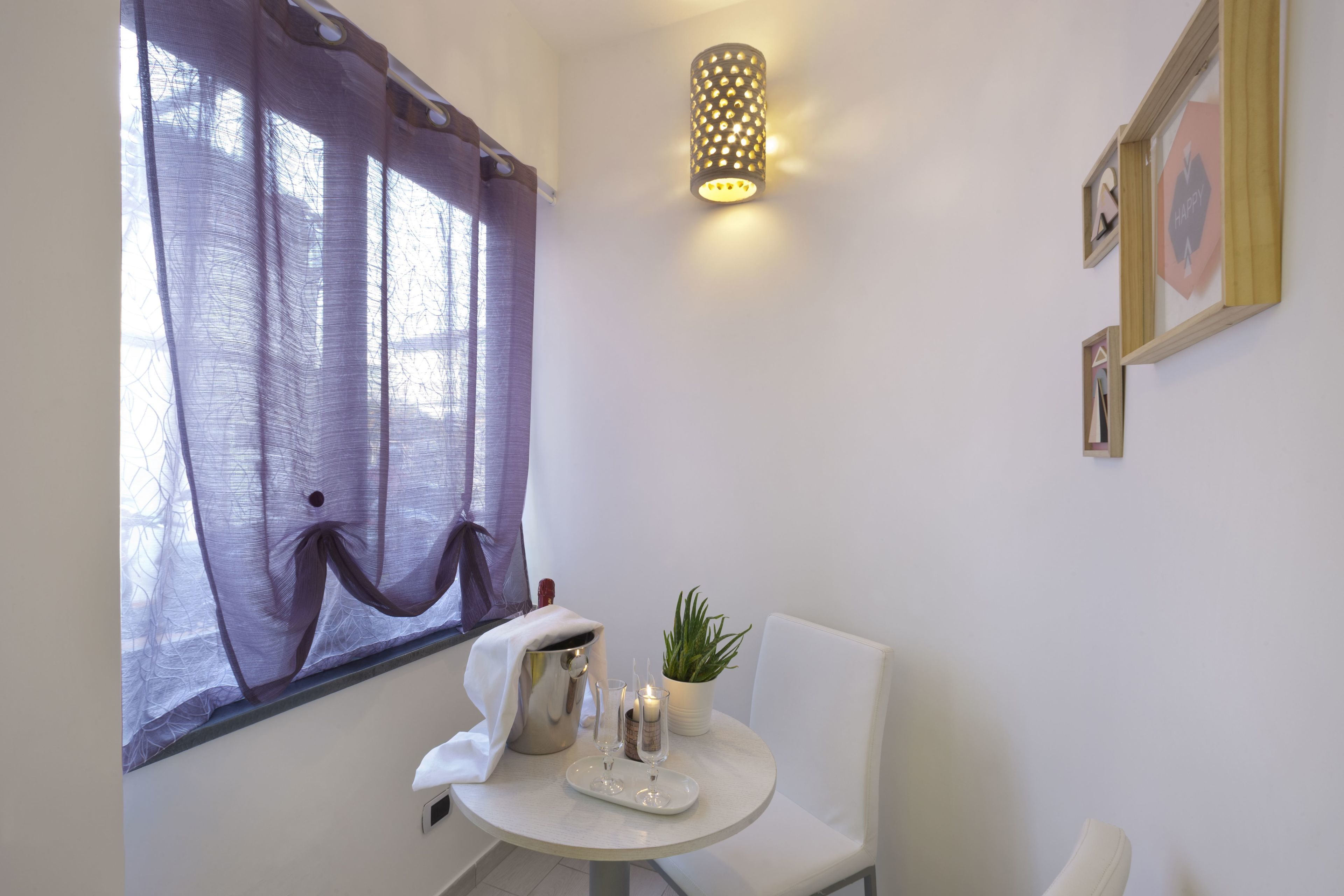 A room with a round table, a potted plant, a candle, and a lamp.