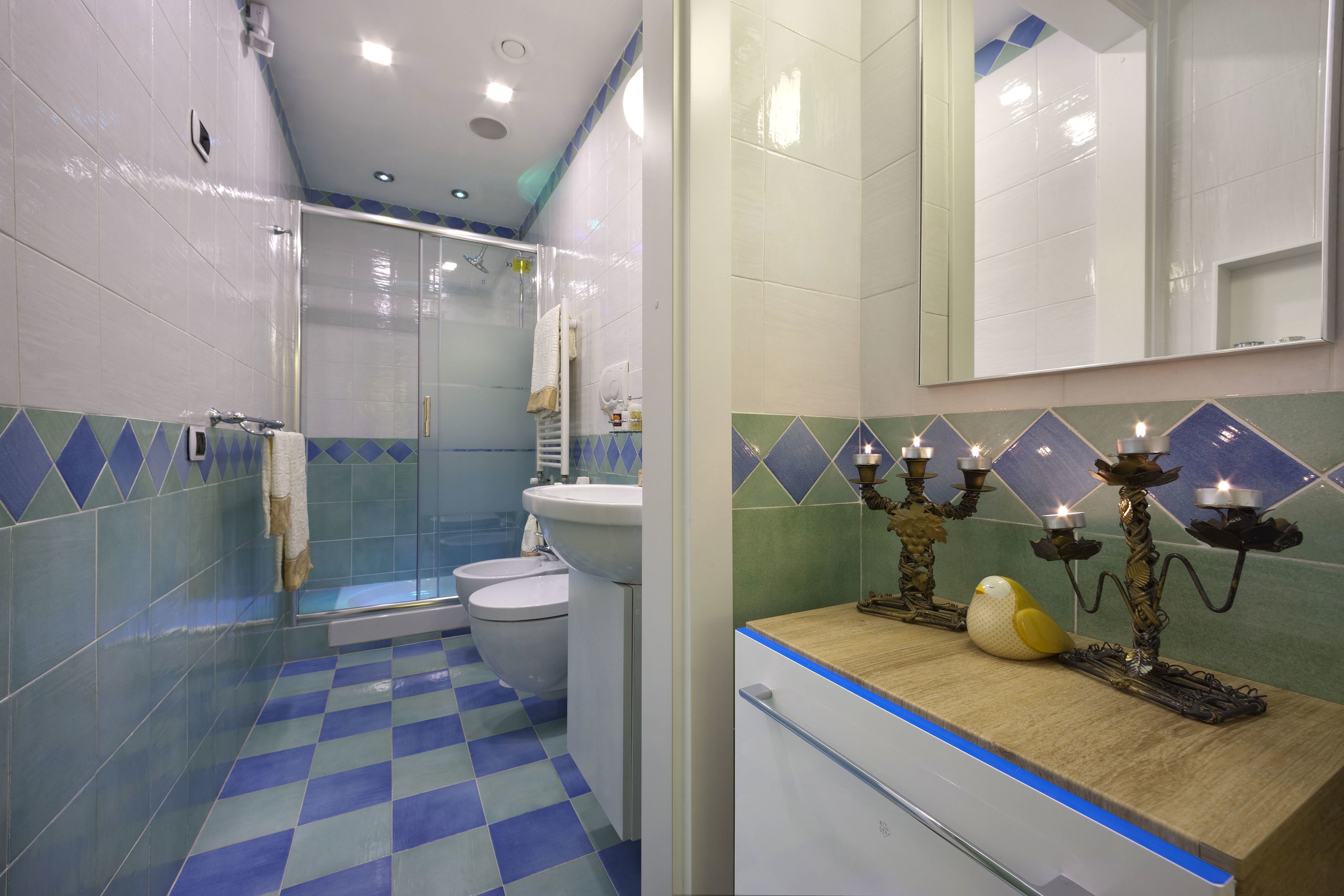 A bathroom with a checkered floor, a shower, a toilet, a sink, and a mirror.