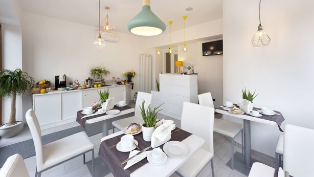 Een moderne eetruimte met witte meubels, een centrale tafel met een plant en hanglampen.