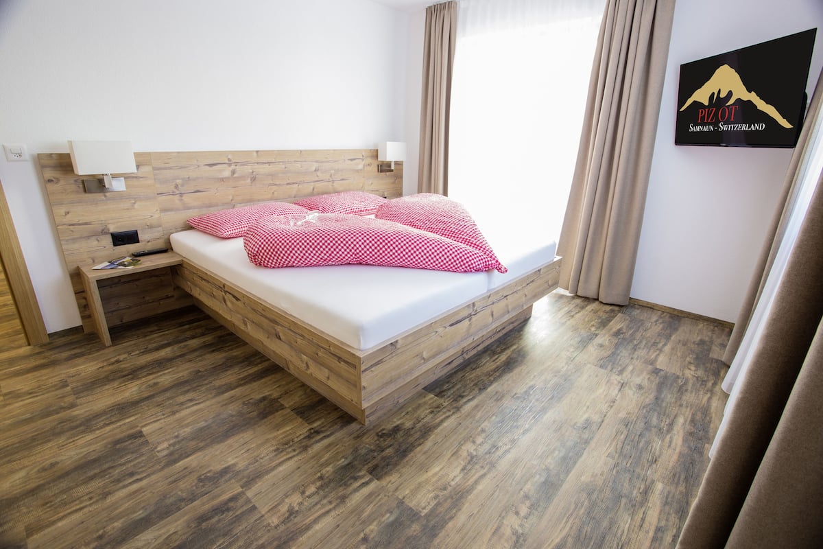 Una habitación de hotel con una cama de madera, paredes blancas y un cartel en la pared.