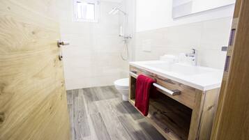 Ein Badezimmer mit einem Holzwaschtisch, einem weißen Waschbecken und einer Dusche.