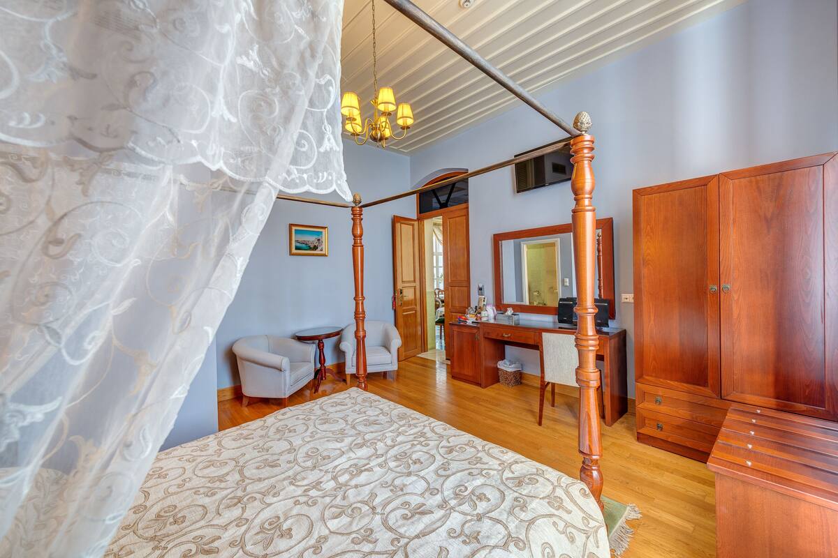 Un dormitorio con cama con dosel, muebles de madera y un espejo grande.