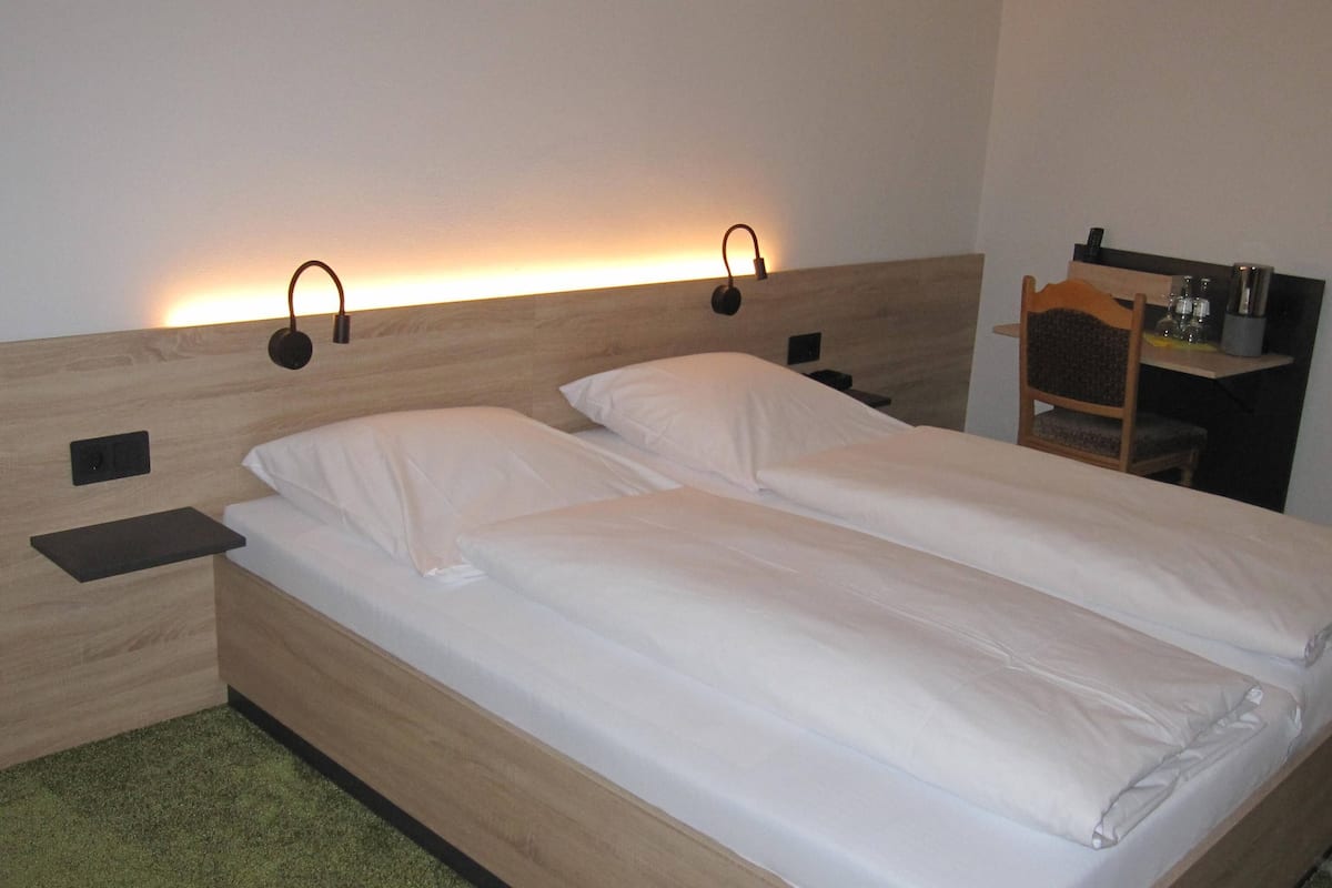 A double bed with white linens, two bedside tables, and wall-mounted reading lights.