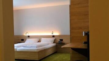 Een moderne slaapkamer met een groot bed, een houten hoofdbord en een groen vloerkleed.